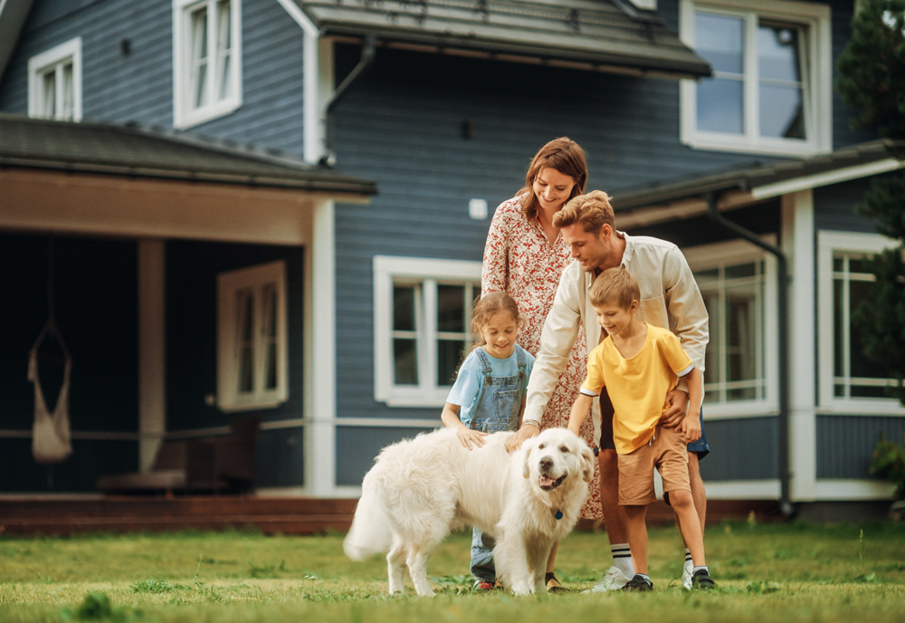 family of four with their golden retriever dog in the front yard of their blue and white multi story house